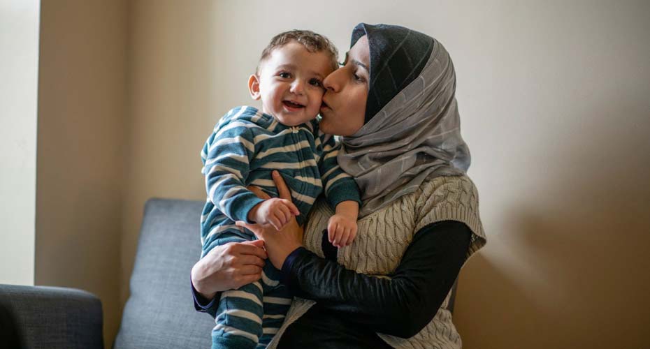 Woman wearing a head scarf and holding a young child